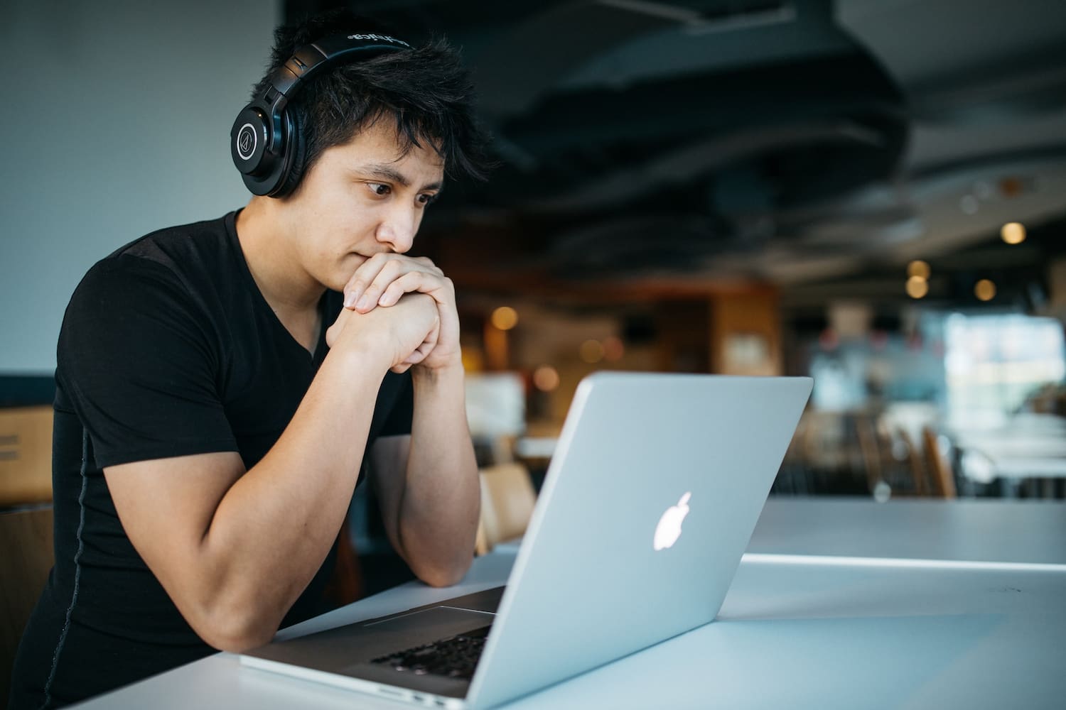 Hombre con auriculares mirando ordenador portátil