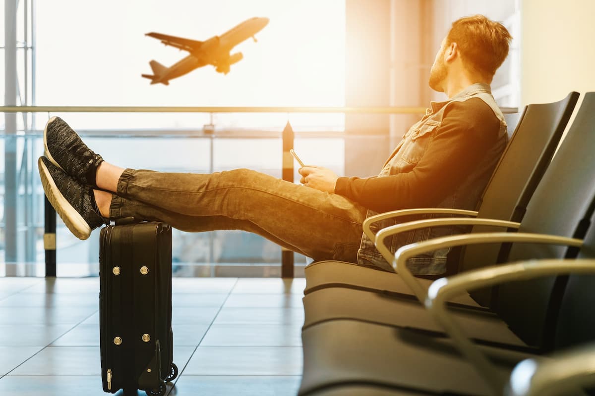Hombre en aeropuerto pensando frases en inglés para viajar