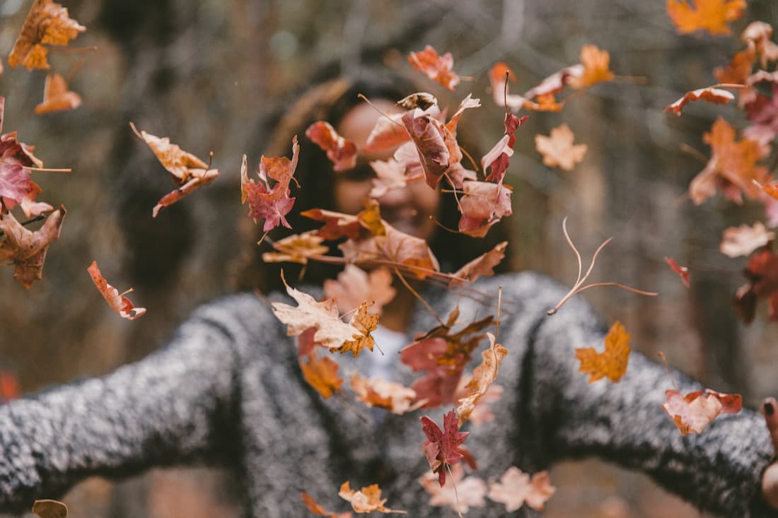 Chica con hojas caídas practicando vocabulario de otoño en inglés